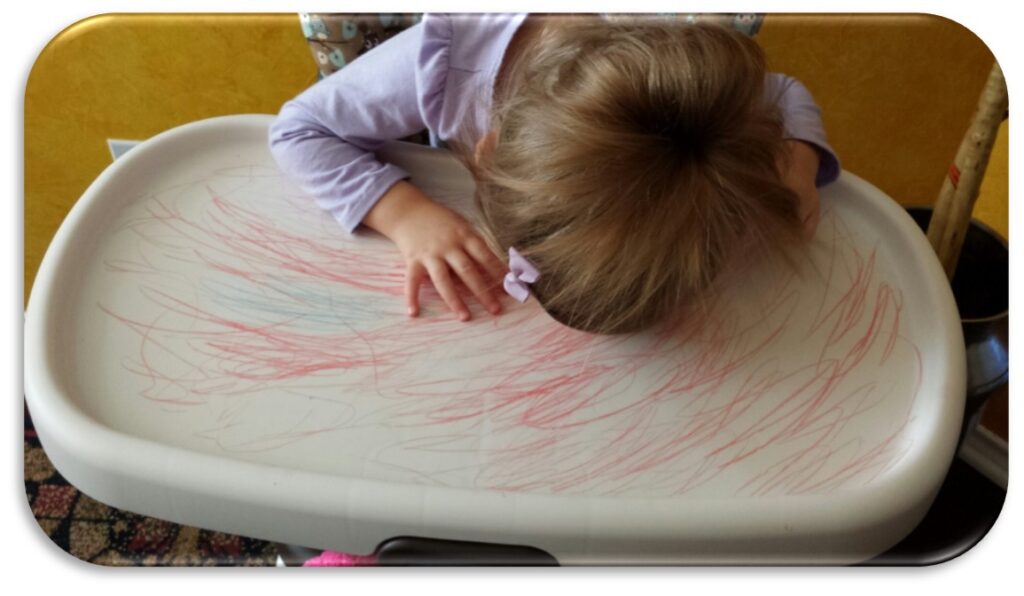 Child coloring on high chair.